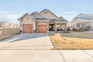 View of front facade featuring driveway, a garage, roof with shingles, covered porch, and fence