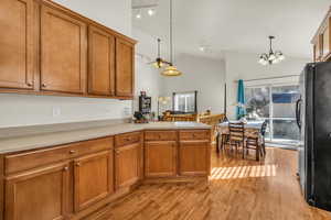 Kitchen featuring brown cabinets, pendant lighting, light countertops, and freestanding refrigerator