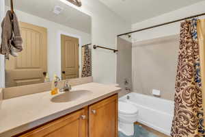 Bathroom with toilet, vanity, tile patterned floors, and shower / bath combo with shower curtain