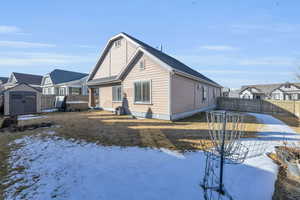 View of snowy exterior with a hot tub, a fenced backyard, a residential view, and a  Shed