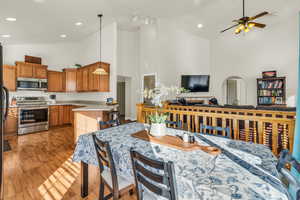 Kitchen with stainless steel appliances, open floor plan, light countertops, brown cabinetry, and pendant lighting