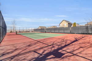 View of tennis court with community basketball court and fence