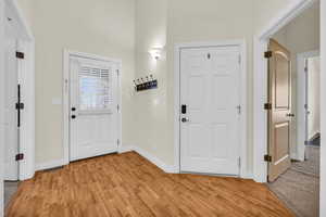 Foyer with light wood finished floors, visible vents, and baseboards