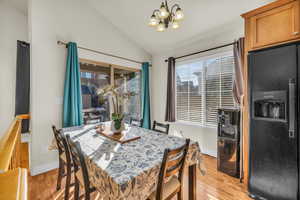 Dining area featuring vaulted ceiling, light wood finished floors, baseboards, and a notable chandelier