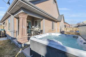 View of home's exterior with cooling unit, fence, and a hot tub