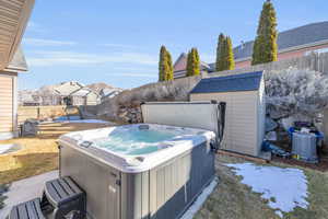 View of yard with a fenced backyard, an outdoor structure, a hot tub, and a storage shed