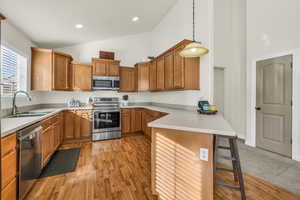 Kitchen featuring hanging light fixtures, stainless steel appliances, a sink, and light countertops