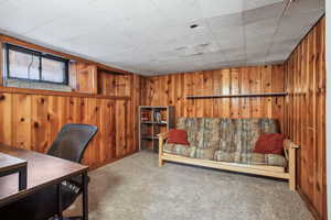 Carpeted home office featuring wooden walls