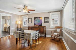 Dining room featuring baseboards, wood finished floors, a ceiling fan, and crown molding