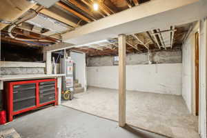 Unfinished basement with stairway and gas water heater