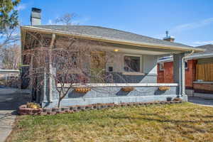 View of front facade featuring a front yard, a chimney, and brick siding