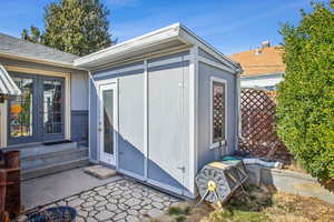 View of outbuilding featuring entry steps, french doors, and fence