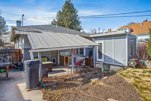 Rear view of house featuring metal roof, a patio, a shingled roof, fence, and a chimney