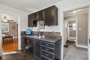 Kitchen with arched walkways, dark countertops, a sink, and crown molding