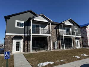 View of front of house with a balcony, stucco siding, a front lawn, and brick siding