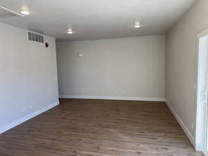 Empty room featuring visible vents, dark wood finished floors, a textured ceiling, and baseboards