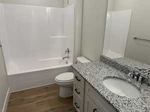 Bathroom with shower / tub combination, vanity, toilet, and wood finished floors