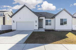 Modern inspired farmhouse featuring a garage, concrete driveway, and board and batten siding