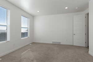 Empty room featuring baseboards, recessed lighting, visible vents, and light colored carpet