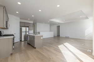 Kitchen with a center island with sink, visible vents, appliances with stainless steel finishes, open floor plan, and light countertops