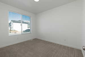 Spare room featuring carpet, visible vents, and baseboards