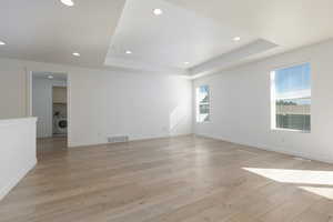 Spare room with visible vents, baseboards, light wood-type flooring, washer / clothes dryer, and a raised ceiling