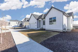 Modern farmhouse style home with a shingled roof, concrete driveway, board and batten siding, a garage, and a residential view