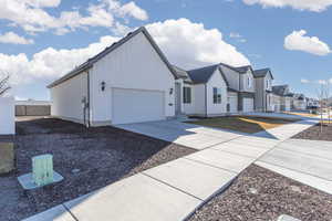 View of front facade with board and batten siding, a residential view, driveway, and an attached garage