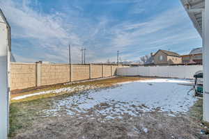 Snowy yard with a fenced backyard