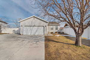 View of front of home featuring a garage, a front yard, concrete driveway, and fence