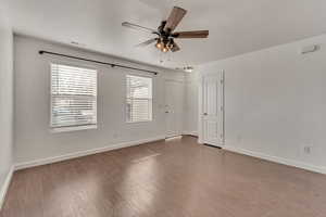 Empty room featuring a ceiling fan, visible vents, dark wood finished floors, and baseboards