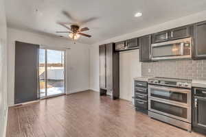 Kitchen with light wood finished floors, tasteful backsplash, appliances with stainless steel finishes, and light countertops