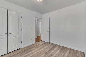 Unfurnished bedroom featuring light wood-style flooring, baseboards, and a closet