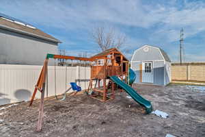 View of playground with a storage shed and a fenced backyard