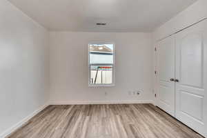 Unfurnished bedroom featuring a closet, baseboards, visible vents, and light wood finished floors