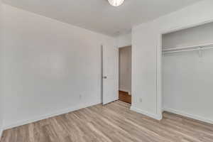 Unfurnished bedroom with light wood-style floors, baseboards, and a closet