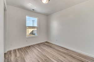 Spare room with visible vents, light wood-style flooring, and baseboards