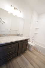 Full bathroom with  shower combination, vanity, toilet, and wood finished floors