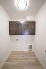 Laundry area featuring hookup for a washing machine, light wood-style flooring, electric dryer hookup, and baseboards