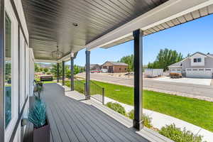 Wooden deck featuring covered porch, a lawn, and a residential view