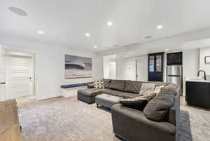 Living area featuring light carpet, baseboards, visible vents, and recessed lighting