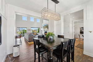 Dining area with dark wood-style floors, a warm lit fireplace, and baseboards