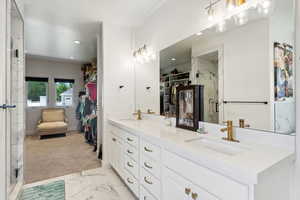 Bathroom with double vanity, a marble finish shower, a walk in closet, and a sink