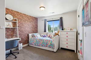 Carpeted bedroom featuring brick wall and visible vents