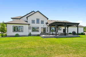 Rear view of house featuring board and batten siding, a shingled roof, a lawn, and a pergola