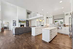 Kitchen with white cabinets, a kitchen island, glass insert cabinets, hanging light fixtures, and light countertops