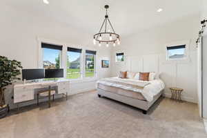 Bedroom featuring a barn door, light colored carpet, a wainscoted wall, a decorative wall, and recessed lighting