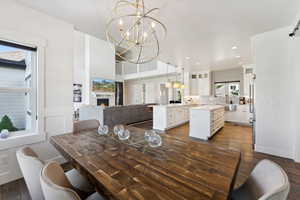 Dining area featuring dark wood-type flooring, recessed lighting, a warm lit fireplace, and a chandelier