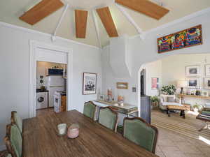 Dining area featuring high vaulted ceiling, arched walkways, washer / clothes dryer, and light tile patterned flooring