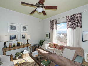 Living area with a ceiling fan and crown molding